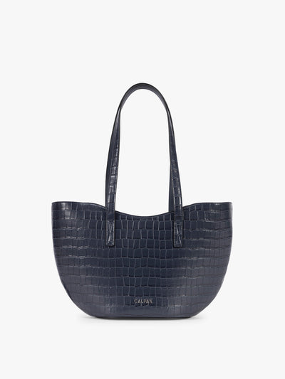 A navy blue crocodile-embossed CALPAK Haven Tulip tote bag with double shoulder straps against a plain white background; AHP2601-NAVY-FAUX-CROC