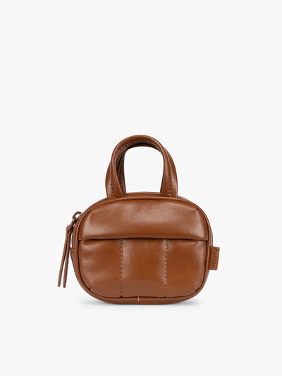 A light Honey Brown vegan leather top-handle CALPAK Luka Zip Bag Charm with a zippered front pocket and a small side strap, shown against a plain white background; ALK2501-HONEY-BROWN-PU