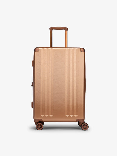 Studio product shot of front-facing CALPAK Ambeur medium 26-inch lightweight hardshell luggage with 360 spinner wheels in copper; LAM1024-COPPER