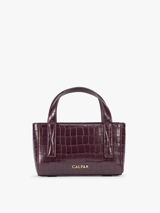 A CALPAK Haven Mini Crossbody Bag in deep red Dark Cherry crocodile-embossed with top handles on a plain white background; AMC2502-DARK-CHERRY-FAUX-CROC