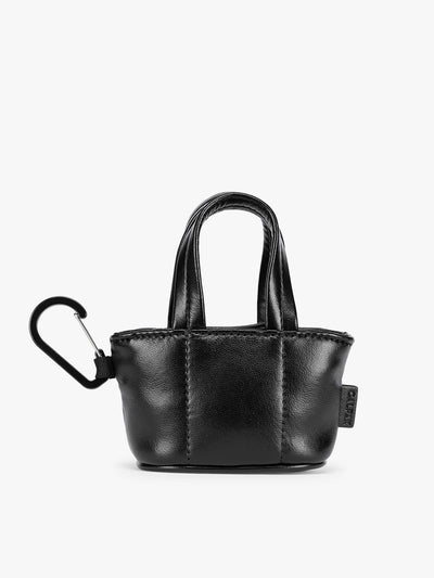 A small Black CALPAK Luka Tote Bag Charm with dual top handles and a black carabiner clip attached to the side, shown against a plain white background; AMT2601-BLACK-PU