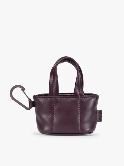 A small deep burgundy Dark Cherry CALPAK Luka Tote Bag Charm with dual top handles and a black carabiner clip attached to the side, shown against a plain white background; AMT2601-DARK-CHERRY-PU