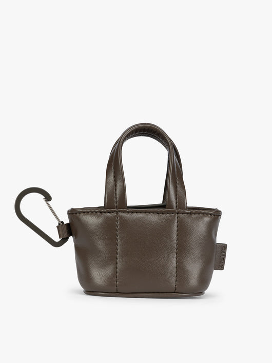 A small dark brown Mushroom CALPAK Luka Tote Bag Charm with dual top handles and a black carabiner clip attached to the side, shown against a plain white background; AMT2601-MUSHROOM-PU