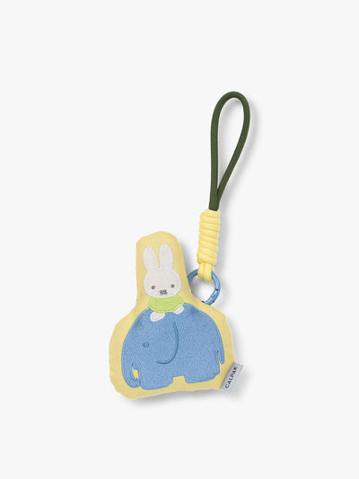 Plush Miffy x CALPAK Pluffy Bag Charm keychain with a yellow border and Miffy on a blue elephant on a white background; APLF2501-MIFFY-ELEPHANT