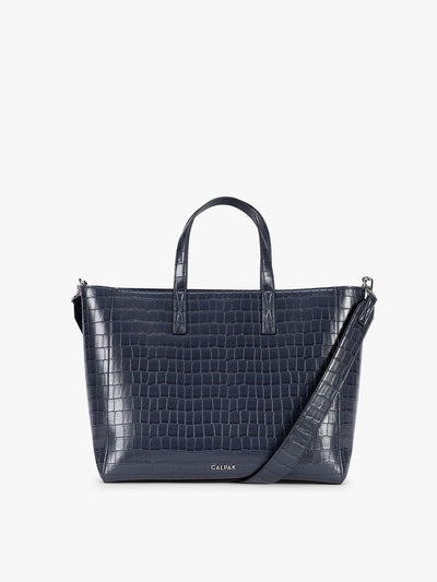 A navy CALPAK Haven 15" Laptop Tote in Navy blue crocodile-embossed with dual top handles and a matching shoulder strap against a plain white background; ATS2501-NAVY-FAUX-CROC
