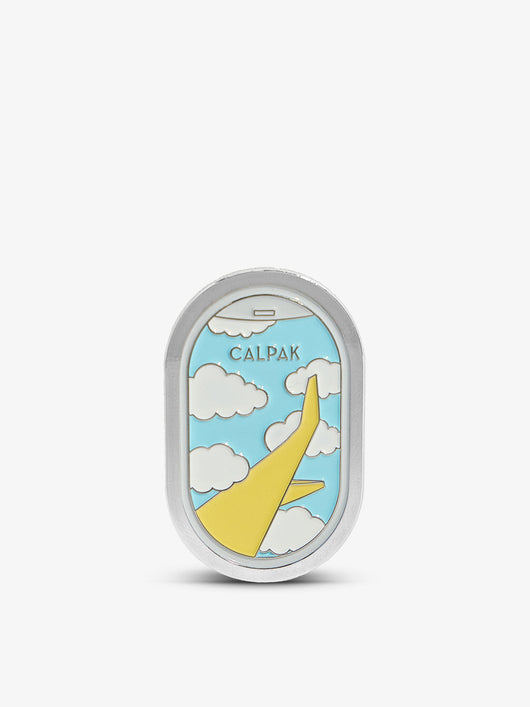 Oval enamel pin with silver backing featuring yellow airplane, white clouds, and blue sky with CALPAK text.
