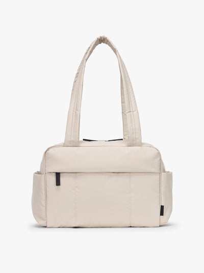 CALPAK Mini Duffel in white Oatmeal front view with puffy exterior, interior and exterior pockets, and padded shoulder straps; DLM2501-OATMEAL