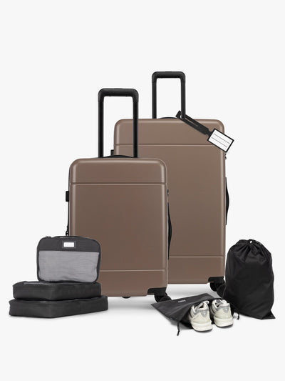 CALPAK Hue Starter Bundle in brown Chocolate that comes with Large and Carry On Luggage, Luggage Tag, Two Black Pouches, and Three Black Packing Cubes shown on a white background; LHU8000-CHOCOLATE