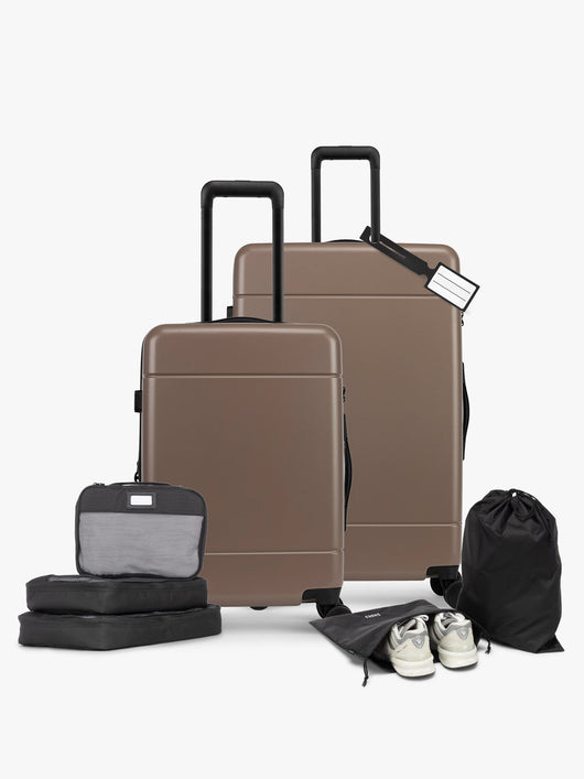 CALPAK Hue Starter Bundle in brown Chocolate that comes with Large and Carry On Luggage, Luggage Tag, Two Black Pouches, and Three Black Packing Cubes shown on a white background; LHU8000-CHOCOLATE