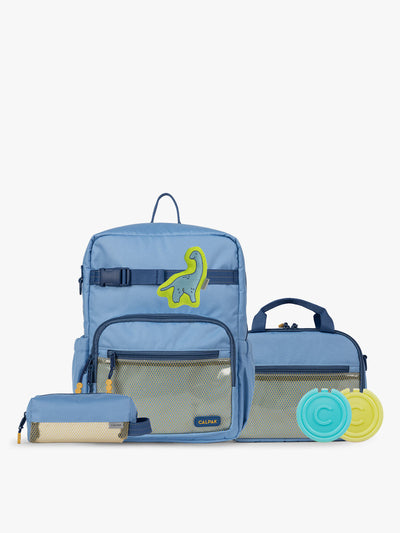 CALPAK Kids Collection Medium Kids Backpack Bundle in Blue that includes Kids Lunch Bag, Kids Pencil Case, blue and green Dinosaur Pluffy Bag Charm, and Set of 2 Ice Packs in a kid's room; BCKM5000-BLUE