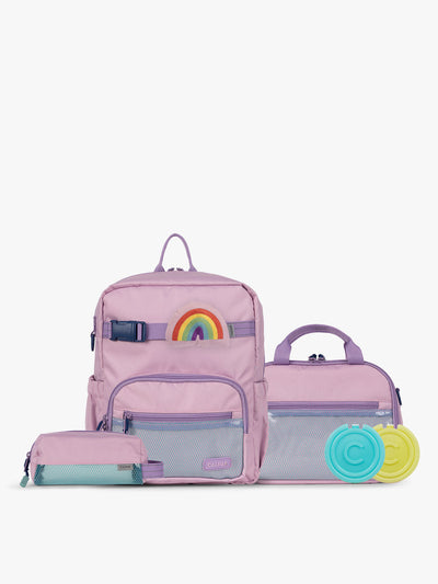 CALPAK Kids Collection Small Kids Backpack Bundle in pink lavender Orchid Pink that includes Kids Lunch Bag, Kids Pencil Case, Rainbow Pluffy Bag Charm, and Set of 2 Ice Packs in a kid's room; BCKS5000-ORCHID-PINK