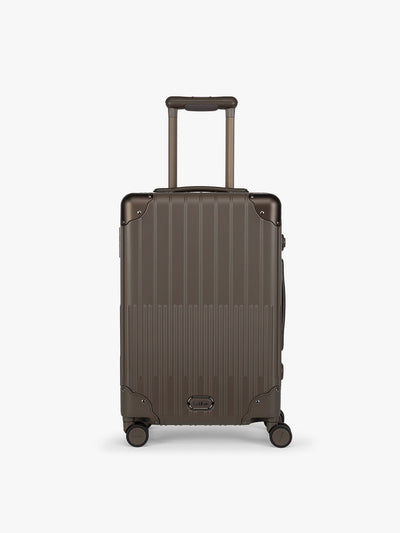 CALPAK Vault brown Mushroom hard-shell spinner Carry On Luggage with a telescoping handle extended, featuring a black leatherette side handle and trim, set against a plain light gray background; LVT1020-MUSHROOM