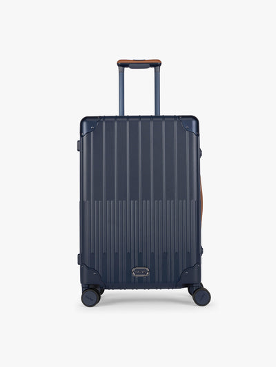 CALPAK Vault Luggage blue Navy hard-shell spinner suitcase with a ribbed vertical design, shown from the front against a clean white background; LVT1024-NAVY