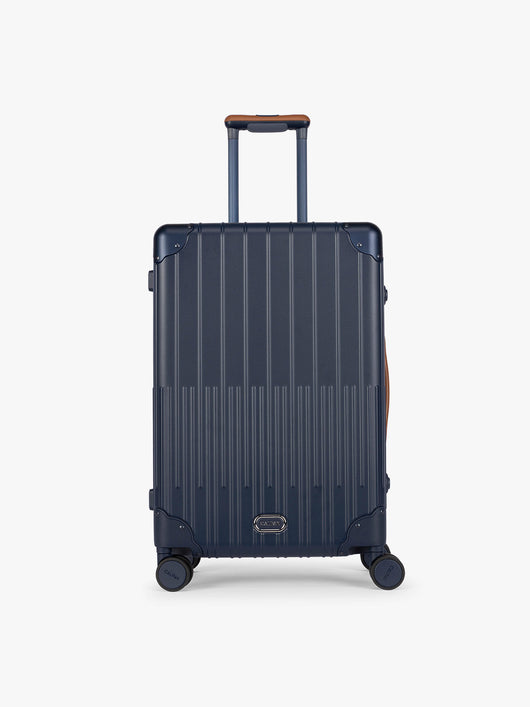 CALPAK Vault Luggage blue Navy hard-shell spinner suitcase with a ribbed vertical design, shown from the front against a clean white background; LVT1024-NAVY