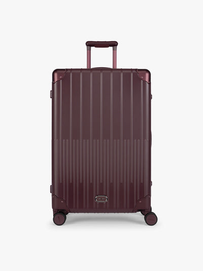 CALPAK Large Vault Luggage in deep red Dark Cherry with hard-shell spinner suitcase with a ribbed vertical design, shown from the front on a light gray background; LVT1028-DARK-CHERRY