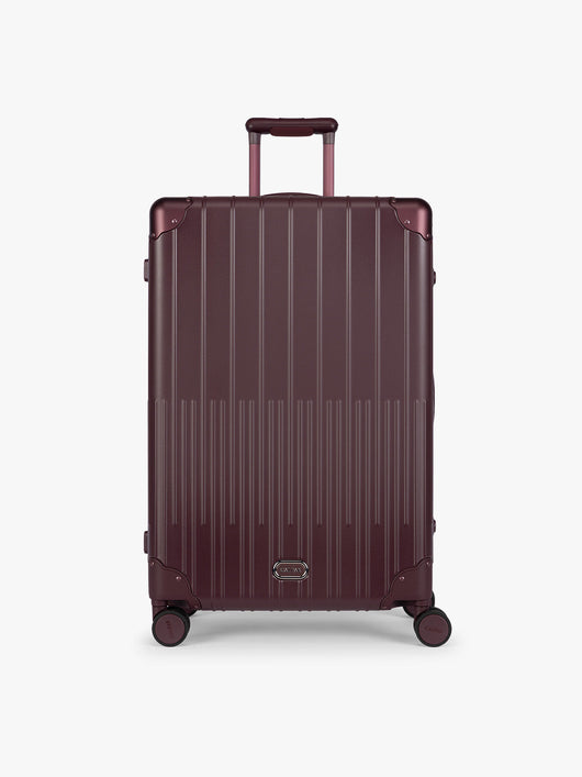 CALPAK Large Vault Luggage in deep red Dark Cherry with hard-shell spinner suitcase with a ribbed vertical design, shown from the front on a light gray background; LVT1028-DARK-CHERRY