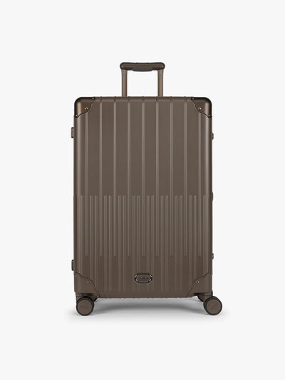 CALPAK Large Vault Luggage in brown Mushroom with hard-shell spinner suitcase with a ribbed vertical design, shown from the front on a light gray background; LVT1028-MUSHROOM