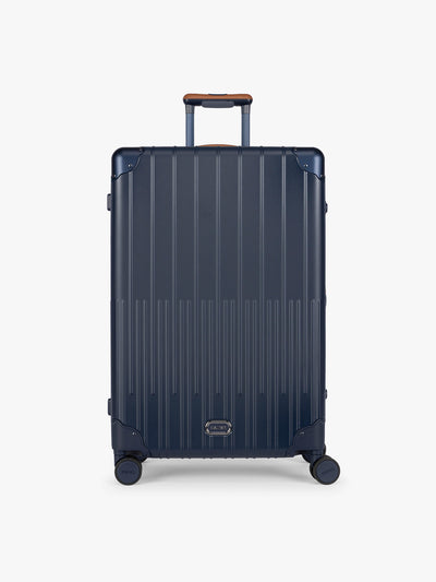 CALPAK Large Vault Luggage in blue Navy with hard-shell spinner suitcase with a ribbed vertical design, shown from the front on a light gray background; LVT1028-NAVY