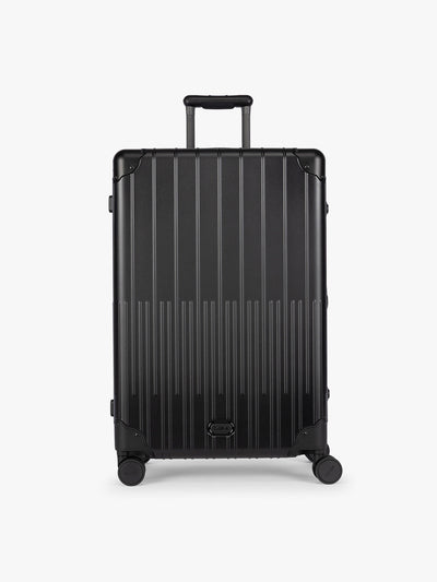 CALPAK Large Vault Luggage in black Onyx with hard-shell spinner suitcase with a ribbed vertical design, shown from the front on a light gray background; LVT1028-ONYX