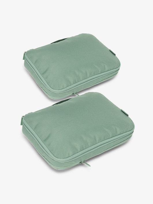 Two sage green rectangular packing cubes with zipper closures and carry handles.