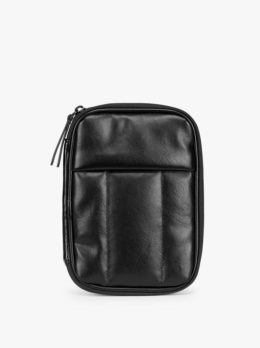  Black CALPAK Luka Zip Passport Wallet in vegan leather with a zippered top and a front pocket, shown on a plain white background; PZW2301-BLACK-PU