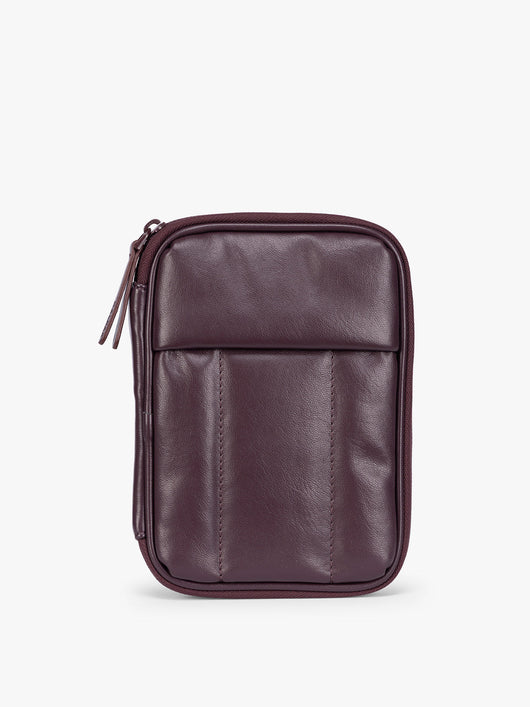 A deep burgundy Dark Cherry CALPAK Luka Zip Passport Wallet in vegan leather with a zippered top and a front pocket, shown on a plain white background; PZW2301-DARK-CHERRY-PU