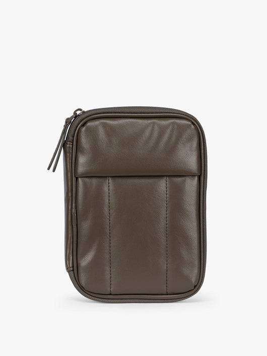 A dark brown Mushroom CALPAK Luka Zip Passport Wallet in vegan leather with a zippered top and a front pocket, shown on a plain white background; PZW2301-MUSHROOM-PU